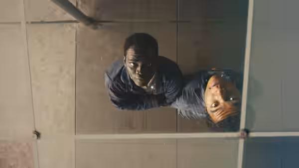 Two young men lying on a glass floor viewed from above