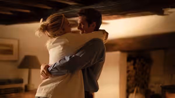 Tobias (Andrew Garfield) and Almut (Florence Pugh) share a warm hug indoors