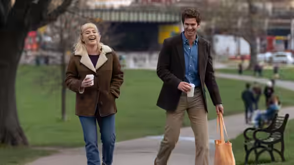 Tobias (Andrew Garfield) and Almut (Florence Pugh) walk through a park with coffee
