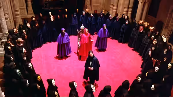 Figures in cloaks and masks gathered in a circle on a red carpet