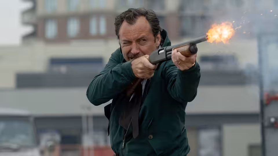 Terry Husk (Jude Law) firing a shotgun on an urban street