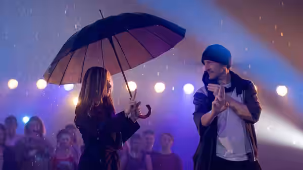 couple sharing an umbrella in the rain at a nighttime event