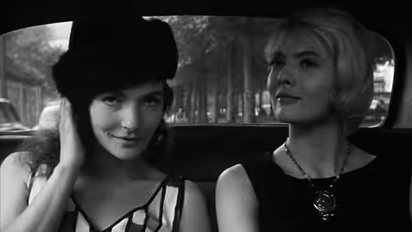 Cléo rides in a taxi beside a young woman wearing a large hat