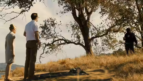 Melanie (Chloë Sevigny) stands with a man outdoors beside a large tree