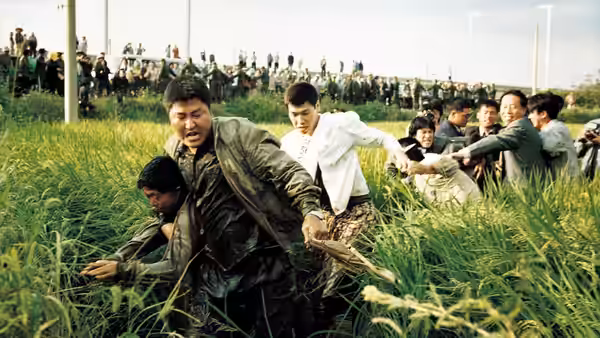 Detective Park Doo-man (Song Kang-ho) running through a grassy field with others